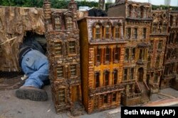 A man works around miniature brownstone buildings during the preparations for the annual Holiday Train Show at the New York Botanical Garden in New York, Nov. 11, 2021.
