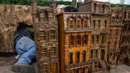 A man works around miniature brownstone buildings during the preparations for the annual Holiday Train Show at the New York Botanical Garden in New York, Nov. 11, 2021.