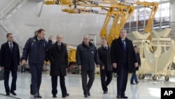 Russian President Vladimir Putin, third left, escorted by Russian Federal Space Agency head Igor Komarov, second left, walks through a working hall while visiting the Vostochny Cosmodrome near Uglegorsk, the city in eastern Siberia in the Amur region, Russia, October 14, 2015.