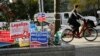 A cyclist peddles past a DC Cannabis Campaign sign, second from left, in Washington, D.C., Nov. 4, 2014. 