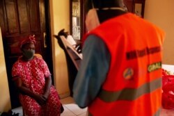 A member of the South Sudanese Ministry of Health Rapid Response Team questions to a woman for testing at her home as she recently contacted with a confirmed COVID-19 coronavirus case in Juba, South Sudan on April 14, 2020.