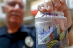 Narcotics detective Will Pfeiffer displays an evidence bag containing methamphetamine before it is destroyed in Barberton, Ohio, Sept. 11, 2019.