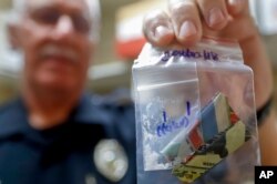 Narcotics detective Will Pfeiffer displays an evidence bag containing methamphetamine before it is destroyed in Barberton, Ohio, Sept. 11, 2019.