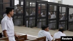 FILE - Islamist defendants stand behind bars in the case known as the "Kerdasa massacre,'' that referred 188 people to court over an attack that killed 14 policemen in 2013, in Cairo, June 23, 2014. 