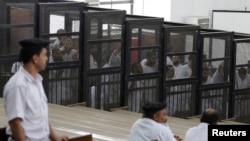 La police surveille des accusés lors d’un procès dans un tribunal du Caire, Egypte, 23 juin 2014.