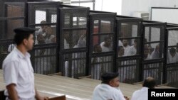 FILE - Islamist defendants stand behind bars in the case known as the "Kerdasa massacre'', that referred 188 people to court over an attack that killed 14 policemen in 2013, in Cairo June 23, 2014. 
