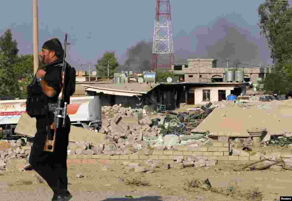 Seorang pejuang Kurdi Peshmerga melewati rumah yang hancur karena serangan udara Amerika di Zummar, yang dikontrol oleh Negara Islam (ISIS) dekat Mosul, Irak (15/9). (Reuters/Ahmad Jadallah)