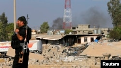 FILE - A Kurdish Peshmerga fighter walks past a house destroyed by American air strikes in Zummar, Iraq, near Mosul on Sept. 15, 2014. At least five rockets were launched from Zummar toward a U.S. military base in Syria on April 21, 2024.