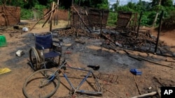 The wheelchair of Amelie Vlonhou, whose body lies nearby, sits beside a burned hut at the Dedjan campsite, near the banks of the Cavally River in western Ivory Coast, May 26, 2011. 