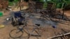 The wheelchair of Amelie Vlonhou, whose body lies nearby, sits beside a burned hut at the Dedjan campsite, near the banks of the Cavally River in western Ivory Coast, May 26, 2011. 