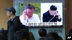 A TV screen shows file footage of South Korean President Moon Jae-in and North Korean leader Kim Jong Un, right, during a news program at the Seoul Railway Station in Seoul, South Korea, Saturday, April 21, 2018. (AP Photo/Ahn Young-joon)