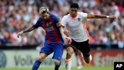 Enzo Perez de Valence, à droite, en duel avec Lionel Messi du FC Barcelone, à gauche, lors du match de football de la Liga espagnole entre Valence et le FC Barcelone au stade Mestalla à Valence, en Espagne, 22 octobre 2016. 