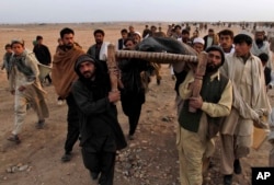 FILE - Afghan people carry the body of a civilian killed in a suicide bombing on a small group of tribal elders and government workers in Khogyani district near Jalalabad, Nangarhar province east of Kabul, Afghanistan, Feb. 22, 2010.