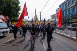 Anti-coup protesters march with flags during a demonstration in Yangon, Myanmar, March 26, 2021.