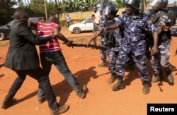 FILE - A supporter of Uganda's former Prime Minister Amama Mbabazi wrestles with the gun of a policeman, as riot police disperse a gathering in Jinja town in eastern Uganda on Sept. 10, 2015. Opposition groups accuse police of harassing voters.