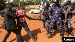 FILE - A supporter of Uganda's former Prime Minister Amama Mbabazi wrestles with the gun of a policeman, as riot police disperse a gathering in Jinja town in eastern Uganda, Sep. 10, 2015.