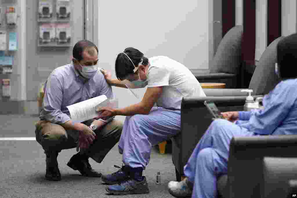 Dr. Thuan Ong, center, reaches out to UW Medicine Chief Medical Officer Dr. Tim Dellit after Ong spoke with deep emotion about his patients who died of the virus before he received a COVID-19 vaccination at the hospital, Dec. 15, 2020, in Seattle, Washington.