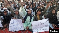 People hold signs as they chant slogans during a protest against satirical French weekly newspaper Charlie Hebdo, in Quetta, Pakistan, Jan. 15, 2015.