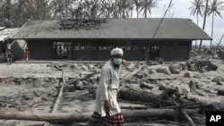 Man walks by destroyed farm school covered with volcanic ashes from eruption of Mount Merapi in Cangkringan, Indonesia, 14 Nov. 2010