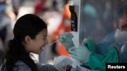 Una niña reacciona mientras le hacen la prueba de la enfermedad por coronavirus (COVID-19) en la Plaza El Salvador del Mundo en San Salvador, El Salvador, el 17 de enero de 2022.