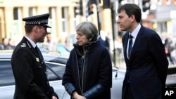 La primera ministra británica, Theresa May, (centro) es informada, el jueves, 15 de marzo de 2018, por miembros de la Policía mientras observa el lugar donde el ex doble agente ruso Sergei Skripal y su hija fueron encontrados críticamente enfermos, en Salisbury, Inglaterra.