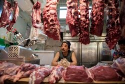 FILE - A butcher waits for customers at a market in Beijing, July 10, 2019. China is taking steps to boost pork supplies as prices soar ahead of a slew of upcoming holidays, including a celebration to mark Communist China's 70th anniversary.