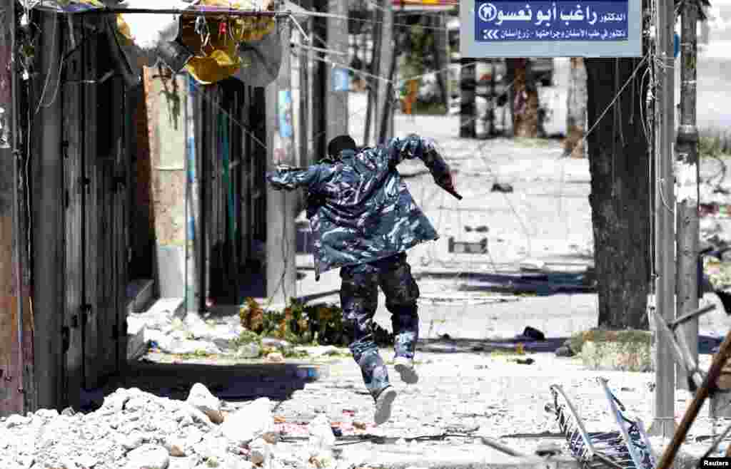A Free Syrian Army fighter runs to take cover from fire from regime forces in Seif El Dawla, August 24, 2012.