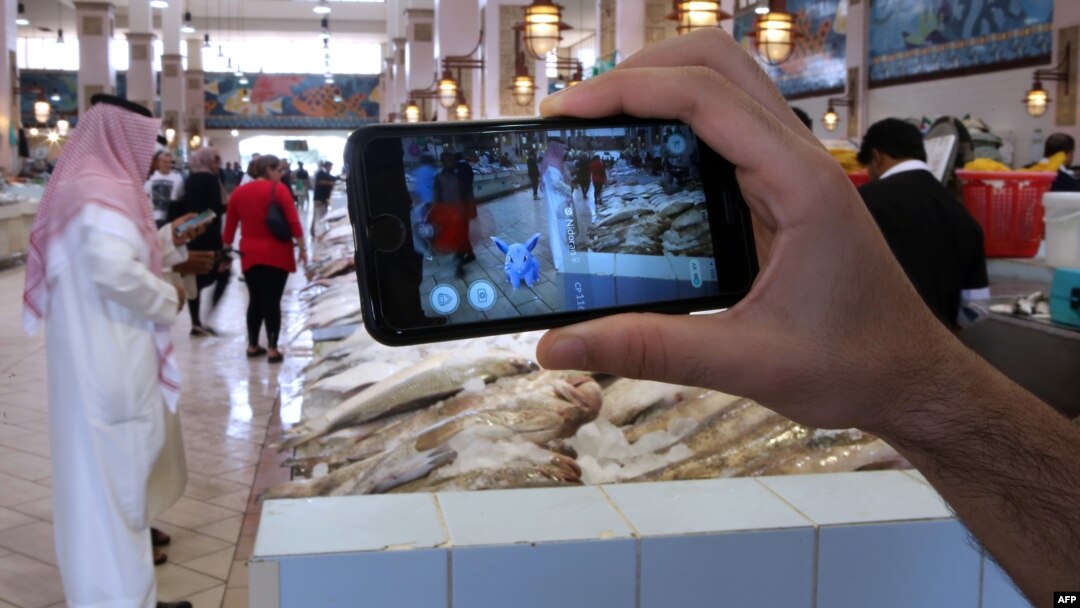 Seseorang menggunakan aplikasi game Pokemon di sebuah pasar ikan di Kuwait City, Kuwait (14/7). (AFP/Yasser al-Zayyat)