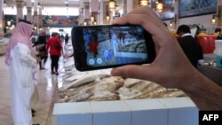 Seseorang menggunakan aplikasi game Pokemon di sebuah pasar ikan di Kuwait City, Kuwait (14/7). (AFP/Yasser al-Zayyat)