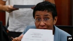 Maria Ressa, the award-winning head of a Philippine online news site Rappler that has aggressively covered President Rodrigo Duterte's policies, shows an arrest form after being arrested by National Bureau of Investigation agents in a libel case, Feb. 13, 2019.