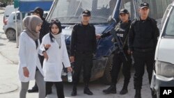 Des Tunisiennes passent devant des policiers à Tunis, 19 mars 2015.