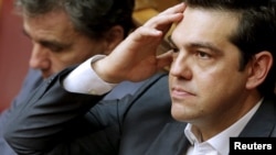Greek Prime Minister Alexis Tsipras, right, reacts as he sits next to Finance Minister Euclid Tsakalotos during a parliamentary session in Athens, Greece, July 15, 2015. 