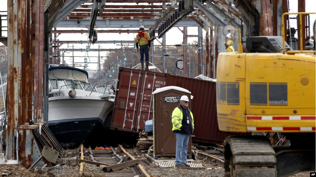 Workers try to clear boats and debris from the New Jersey Transit Morgan draw bridge in South Amboy, New Jersey after Monday's storm surge from Sandy pushed boats and cargo containers onto the train tracks, October 31, 2012.
