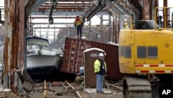 Workers try to clear boats and debris from the New Jersey Transit Morgan draw bridge in South Amboy, New Jersey after Monday's storm surge from Sandy pushed boats and cargo containers onto the train tracks, October 31, 2012.