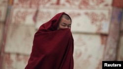 Tibetan monk covers his face as he walks along a street near Labrang Monastery, Xiahe county, Gansu Province, Feb. 11, 2013.