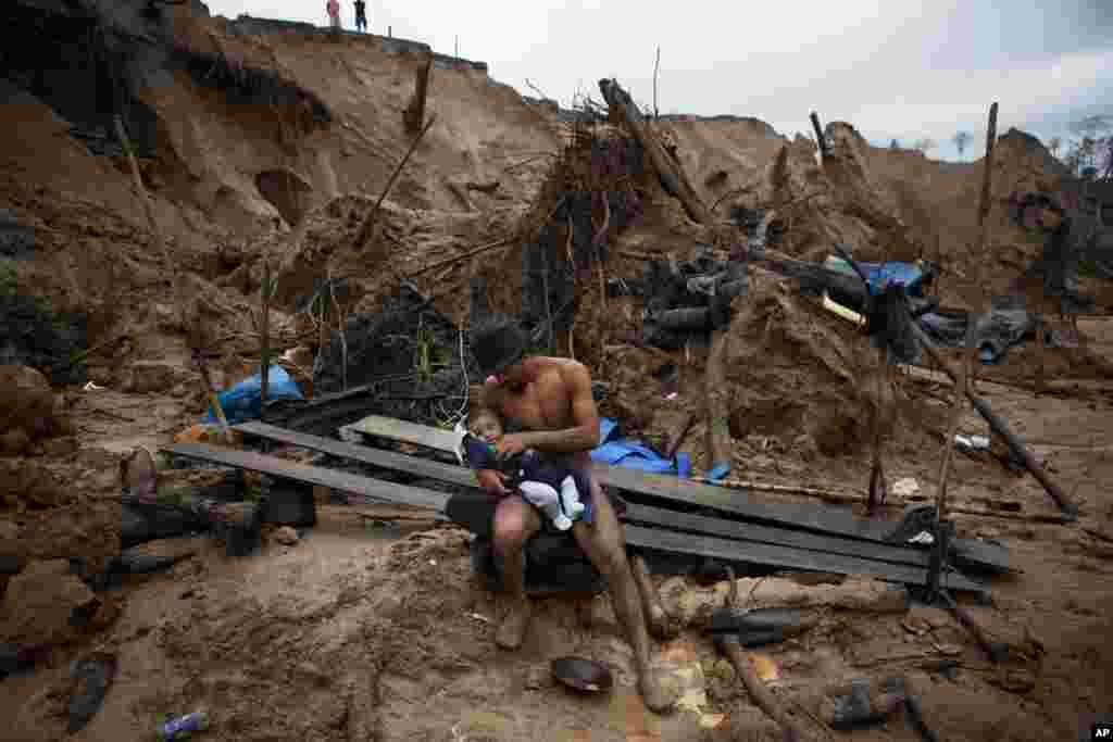 Manuel Espinosa holds his 4-month-old son Edward, brought to him by his wife, as he takes a break from mining gold in La Pampa, located in the Madre de Dios region of Peru, May 2, 2014.