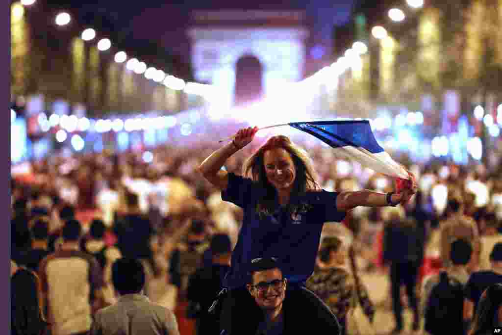 Para penggemar sepak bola berkumpul di Champs Elysees dengan latar Arc de Triomphe, merayakan kemenangan Perancis atas Belgia pada semifinal Piala Dunia 2018 di Paris, 10 Juli 2018.
