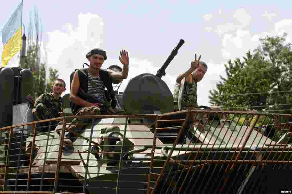 Ukrainian servicemen wave as they drive past in an armoured vehicle in the eastern Ukrainian town of Kramatorsk, Aug. 5, 2014.