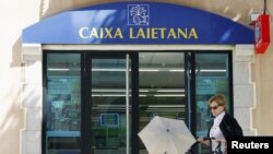 A woman with a stroller walks past a Caixa Laietana's bank office (part of Bankia) in Alella, near Barcelona, June 12, 2012.