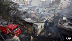 Petugas pemadam kebakaran melewati toko-toko di pasar ban yang dibakar massa di New Delhi, India, 26 Februari 2020.