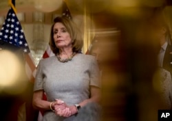 House Speaker Nancy Pelosi of California, accompanied by House Democratic members, listens to a reporter's question after signing a deal to reopen the government on Capitol Hill in Washington, Jan. 25, 2019.