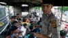An Indonesian policeman guards ethnic Rohingya refugees from Myanmar as they wait inside a police truck for identification by immigration personnel in Lhokseumawe, Feb. 27, 2013. 