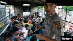 An Indonesian policeman guards ethnic Rohingya refugees from Myanmar as they wait inside a police truck for identification by immigration personnel in Lhokseumawe, Feb. 27, 2013. 