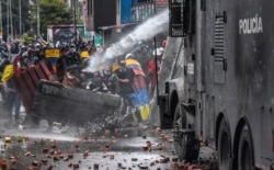 FILE - Police officers spray a water cannon at demonstrators during a protest of Colombian President Ivan Duque's government, in Bogota, June 9, 2021.