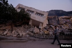 Seorang pria berjalan melewati reruntuhan bangunan dan puing-puing, pasca gempa mematikan, di Antakya, Provinsi Hatay, Turki, 21 Februari 2023. (Foto: REUTERS/Clodagh Kilcoyne)