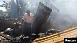 A man clears debris from the mosque that was burnt down in recent violence at Thapyuchai village, outside of Thandwe, in the Rakhine state, Oct. 3, 2013. 