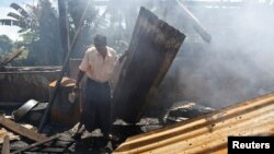 A man clears debris from the mosque that was burnt down in recent violence at Thapyuchai village, outside of Thandwe, in the Rakhine state, Oct. 3, 2013. 