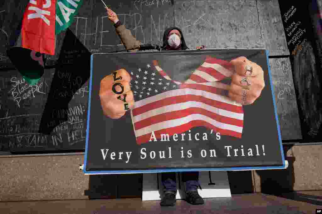 A protester holds a sign across the street from the Hennepin County Government Center in Minneapolis, Minnesota, where testimony continues in the trial of former Minneapolis police officer Derek Chauvin.