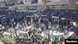 Syrian residents carry the bodies of people whom protesters say were killed by forces loyal to Syria's President Bashar al-Assad, during their funeral in Dara'a June 9, 2012. 