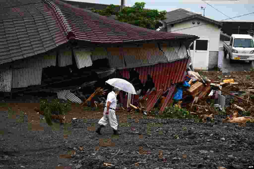 기록적인 폭우로 강이 범람하고 산사태가 잇따른 일본 남부 규슈 지방에 있는 구마모토현의 쓰나기마치 마을에서 주민이 우산을 쓰고 피해 현장을 살펴보고 있다. 
